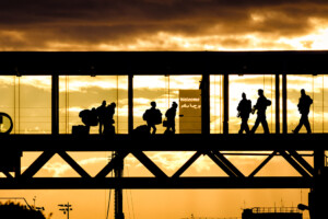 A silhouette of passengers walking through an airport terminal tunnel bridge