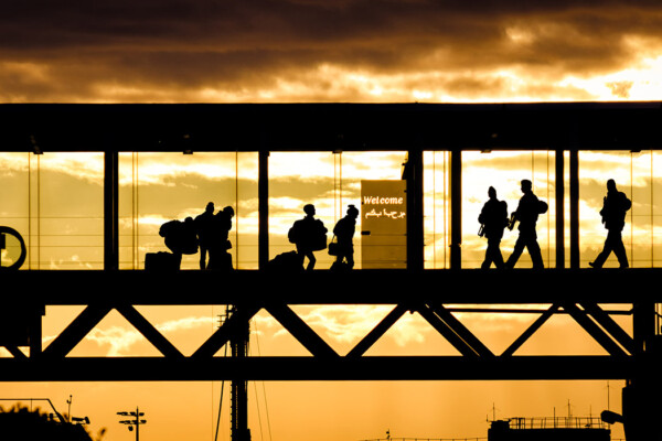 A silhouette of passengers walking through an airport terminal tunnel bridge