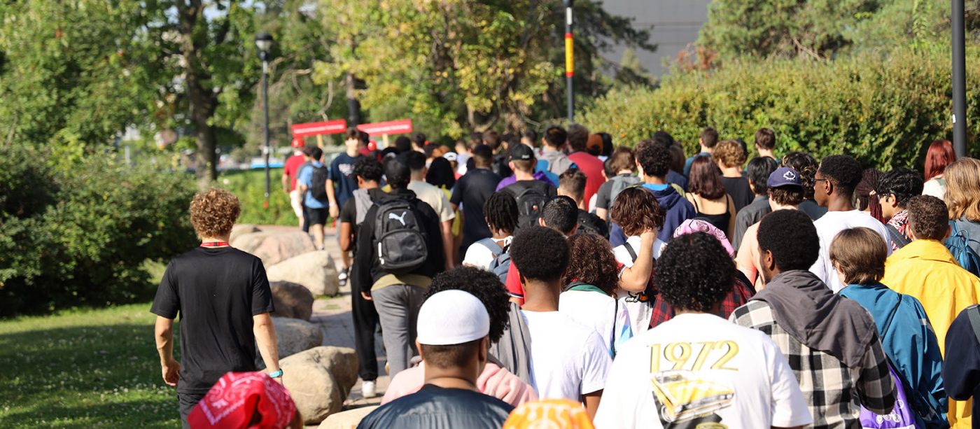 A behind view of dozens of people walking down a path.