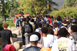 A behind view of dozens of people walking down a path.