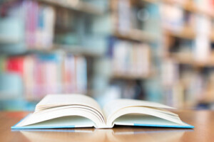 A book sits open at a table in a library.