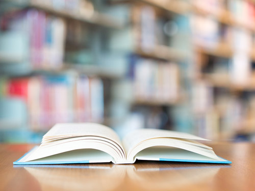 A book sits open at a table in a library.