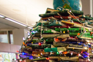A Christmas tree made of books with a globe on top sits in the MacOdrum Library lobby.