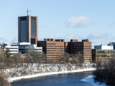 Carleton campus is seen in winter with snow on the banks of the river.