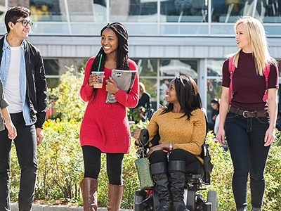 Group of Carleton University walking on campus; the student in the middle is using a wheelchair.
