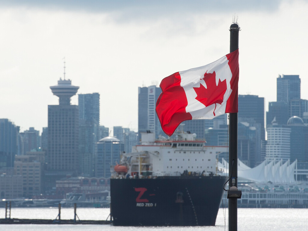 Vancouver skyline behind a Canadian flag in North Vancouver, B.C., March 24, 2020. (THE CANADIAN PRESS/Jonathan Hayward)