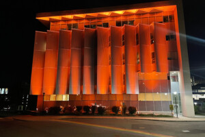 An office building with orange lights projected onto it.