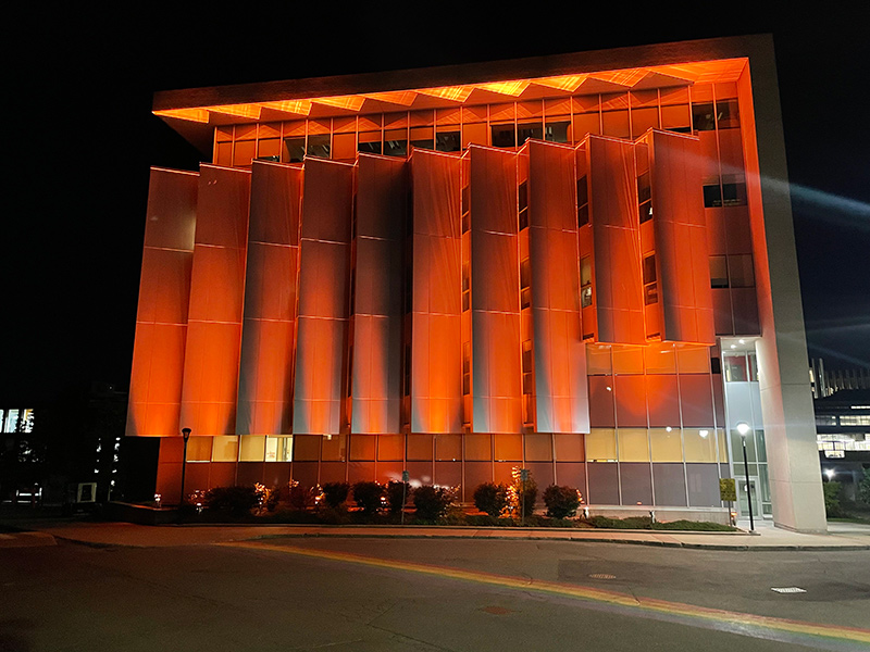 An office building with orange lights projected onto it.
