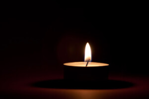 A lit candle against a dark background.