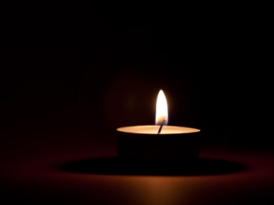 A lit candle against a dark background.