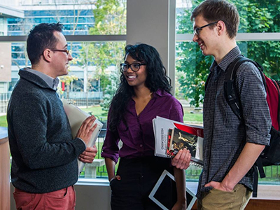 Three people standing in a circle having a discussion.