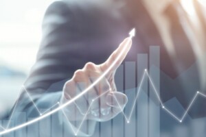A business person in a suit points to a graph indicating economic growth.