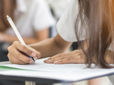 School student taking writing on paper while taking an exam