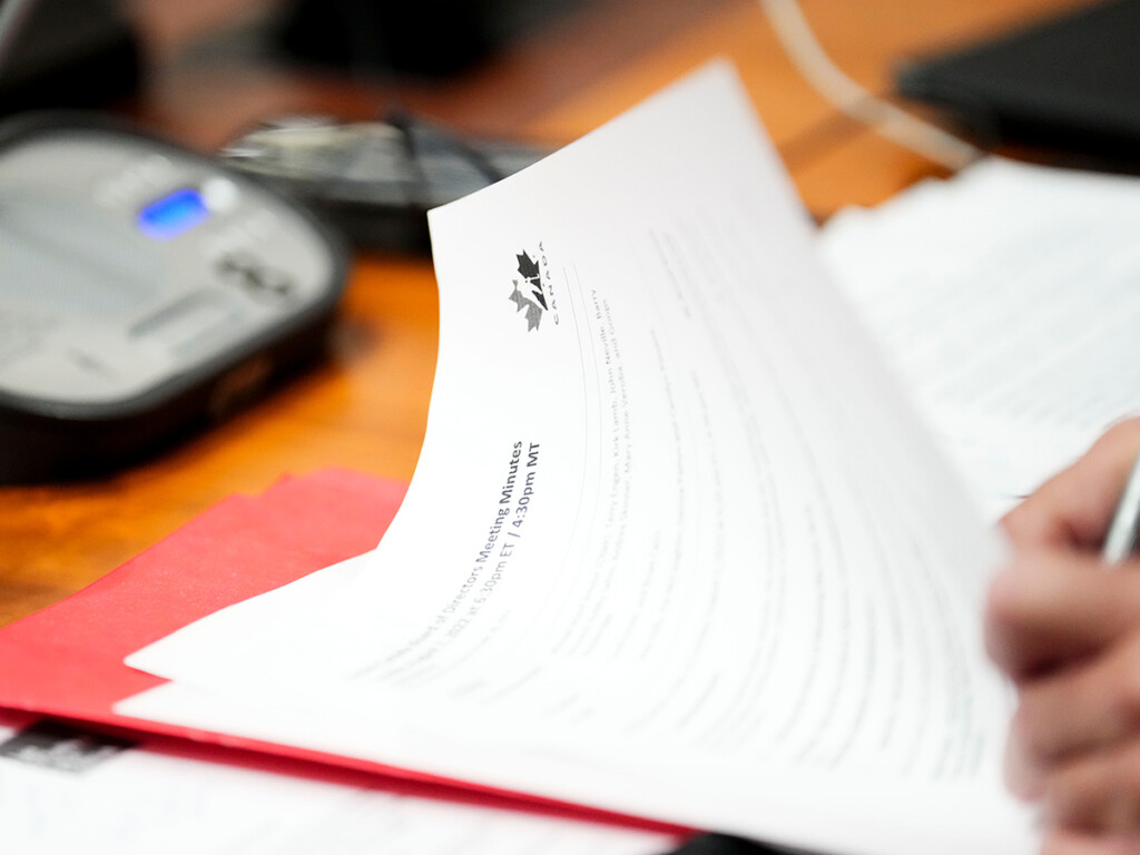 A hand can be seen holding a pen and signing a Hockey Canada document