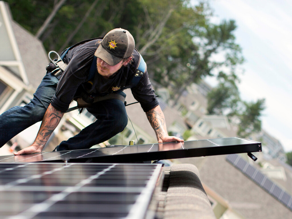 A man installs solar panels on a roof (Photo: Ben McCanna/Portland Portland Press Herald via Getty Images)