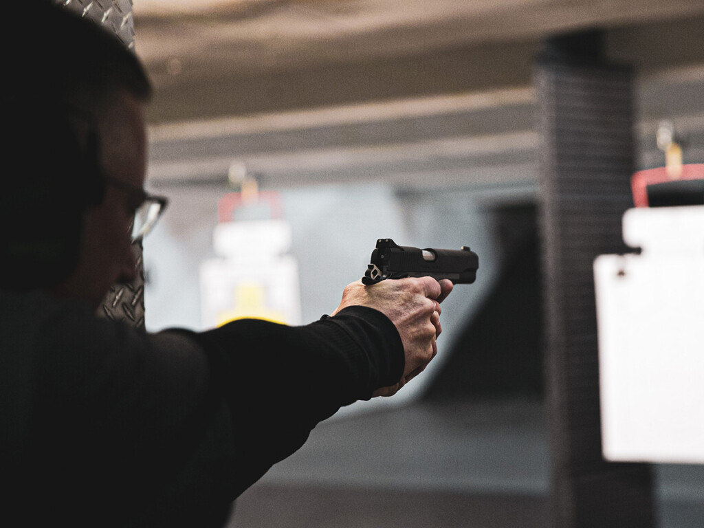 A man prepares to shoot at a paper target at a gun range (Logan Weaver/Unsplash)