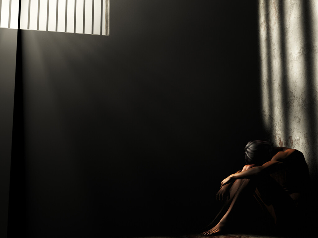 A prisoner in a dark jail cell.