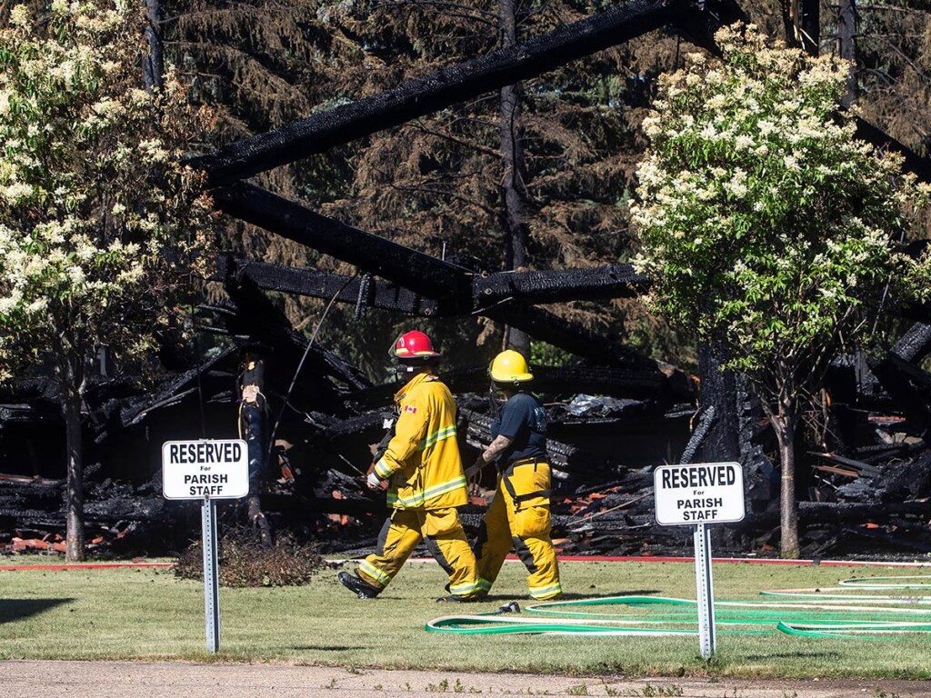 Firefighters walk past the remains of a Catholic church that was on fire, in Morinville, Alta. in June 2021. (THE CANADIAN PRESS/Jason Franson)
