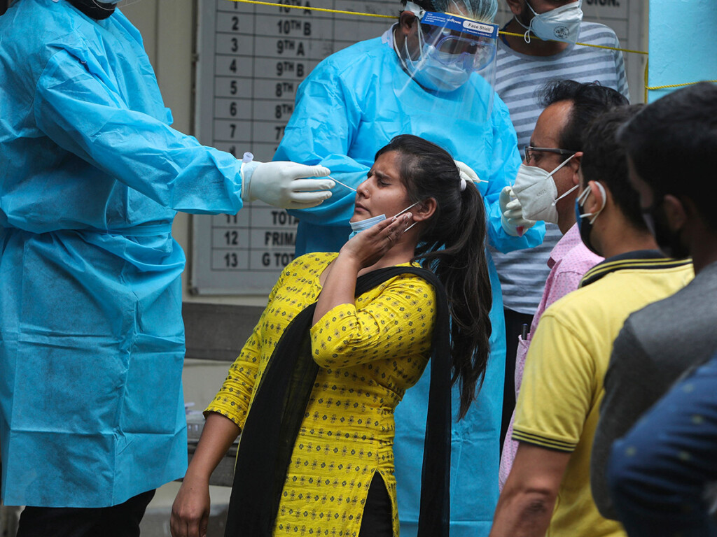 A woman reacts as a health worker tries to take her swab sample to test for COVID-19 in Jammu, India. (AP Photo/Channi Anand)