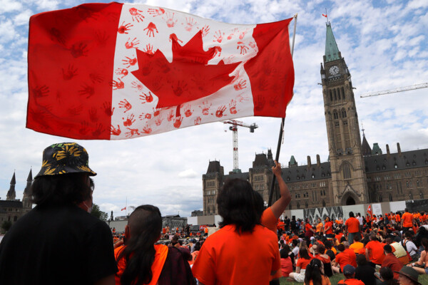 Protesters wave a flag at Parliament Hill in Ottawa at a 'Cancel Canada Day' protest in response to the discovery of hundreds of unmarked graves at Indian Residential Schools. (THE CANADIAN PRESS/ Patrick Doyle)