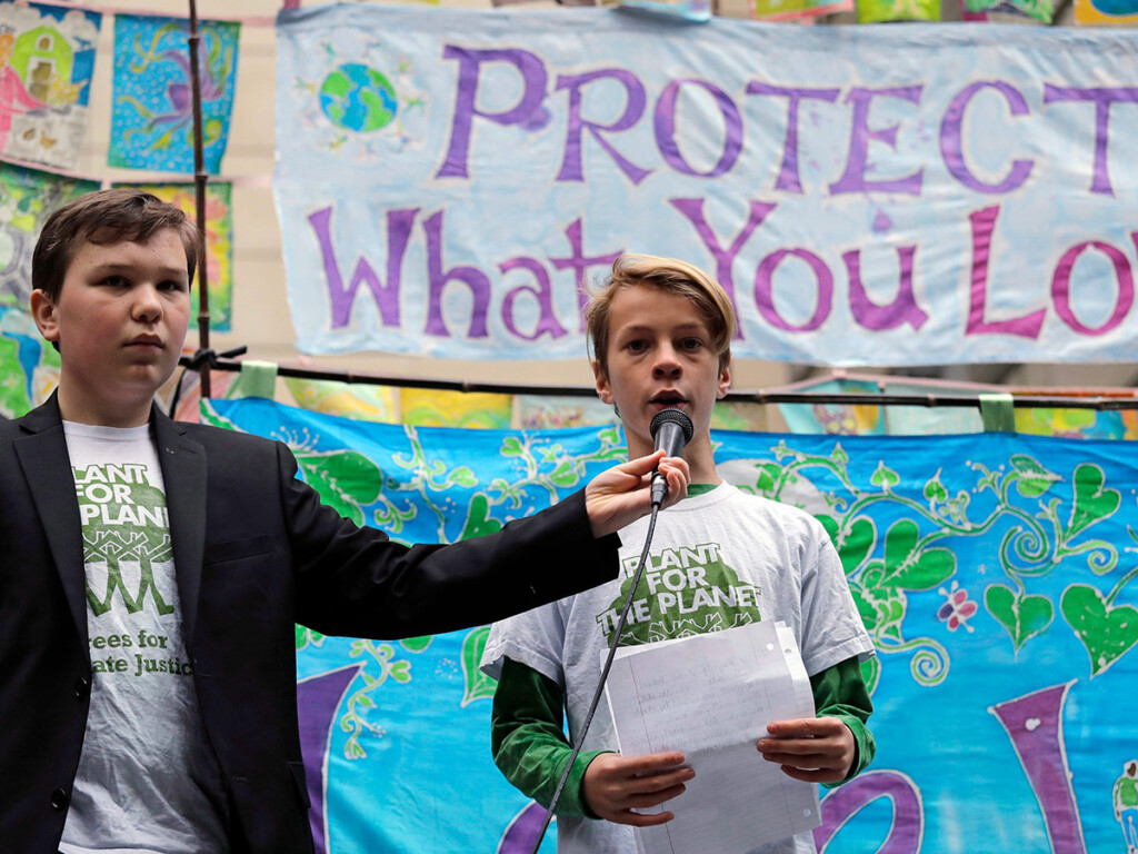 Alex Sayers, left, holds the microphone for Azure Faloona, both 12 years old, at a rally held last October in Seattle in support of a high-profile climate change lawsuit. (AP Photo/Elaine Thompson)