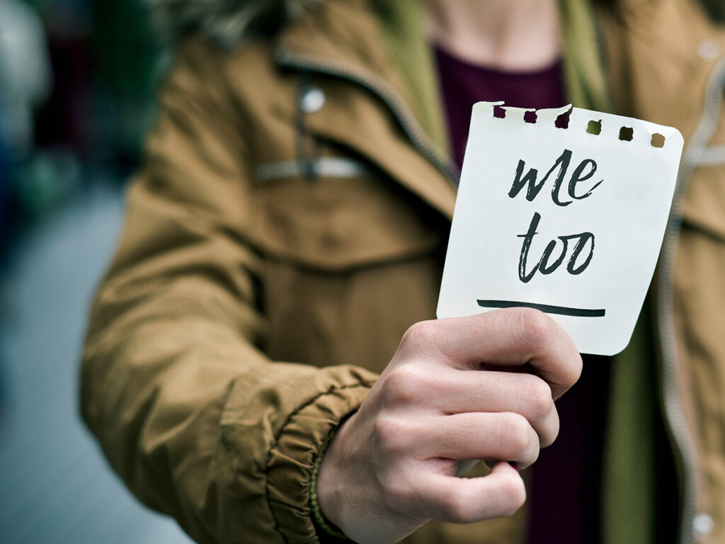 A woman holding a piece of paper with the words #MeToo