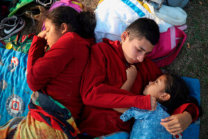 In this April 2018 photo, siblings from El Salvador huddle together on a soccer field in Mexico. awaiting temporary transit visas that would allow them to continue to the U.S. border, where they hoped to request asylum. (AP Photo/Felix Marquez)