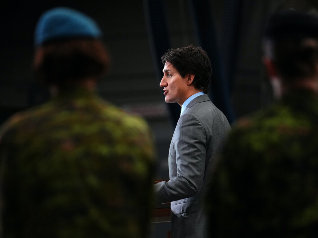 Canadian Prime Minister Justin Trudeau standing in front of two members of the Canadian Armed Forces