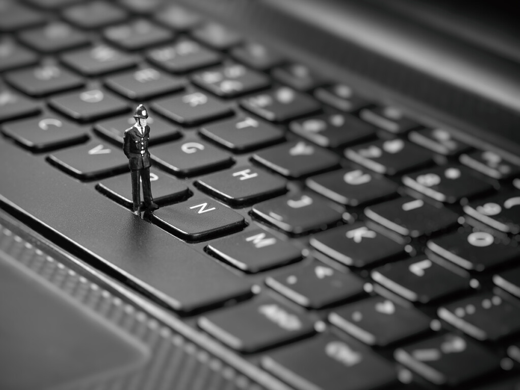 A toy police officer standing on a computer keyboard.