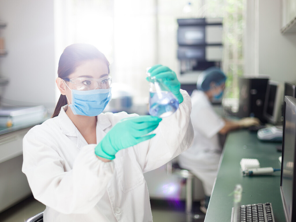 A female scientist holds a flask in a lab. (Shutterstock)