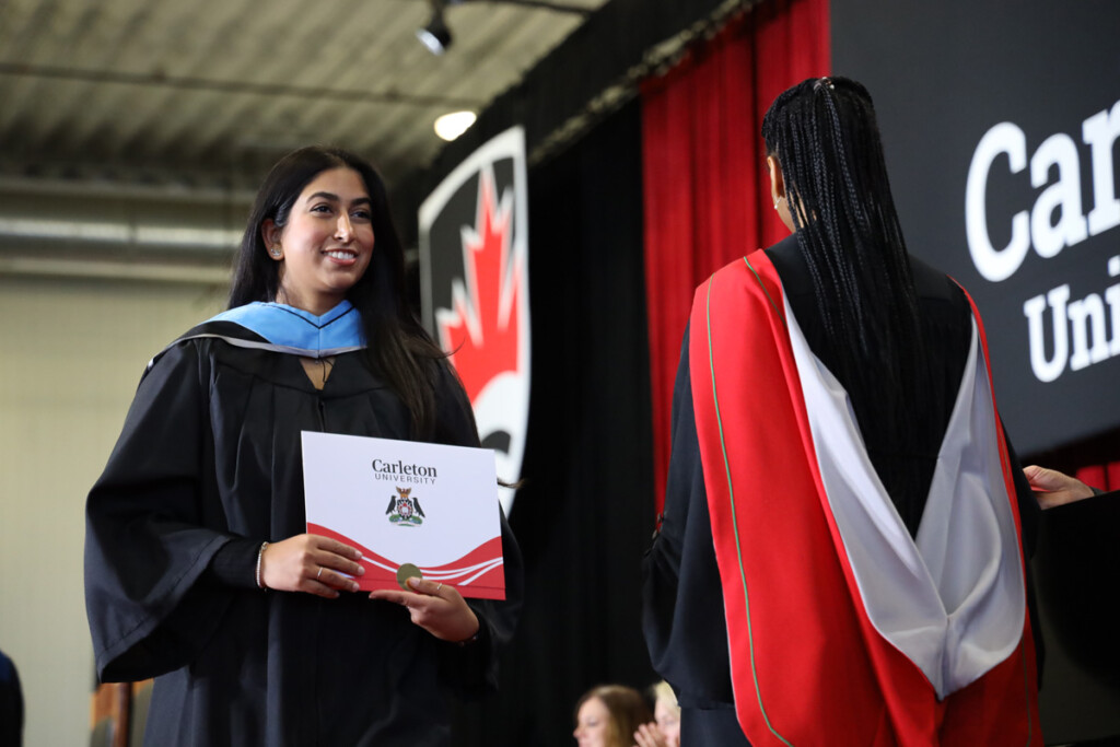 A graduate receives a degree on stage as Carleton Celebrates Fall Graduates