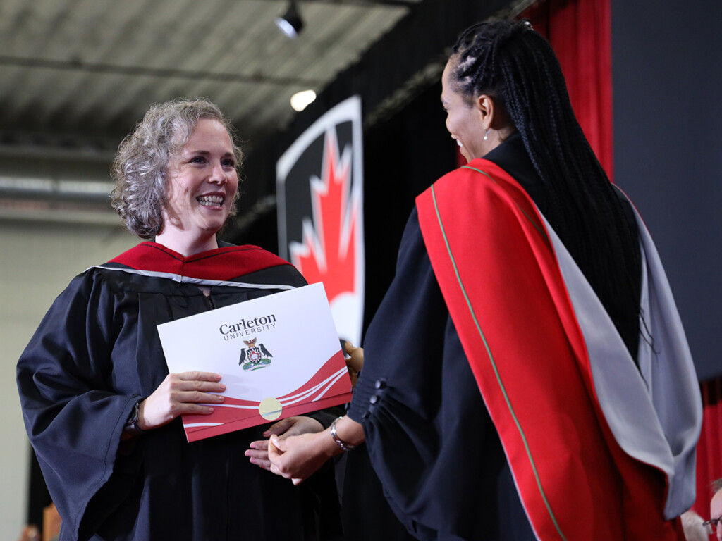 A student accepts a degree on stage as Carleton Celebrates Fall Graduates