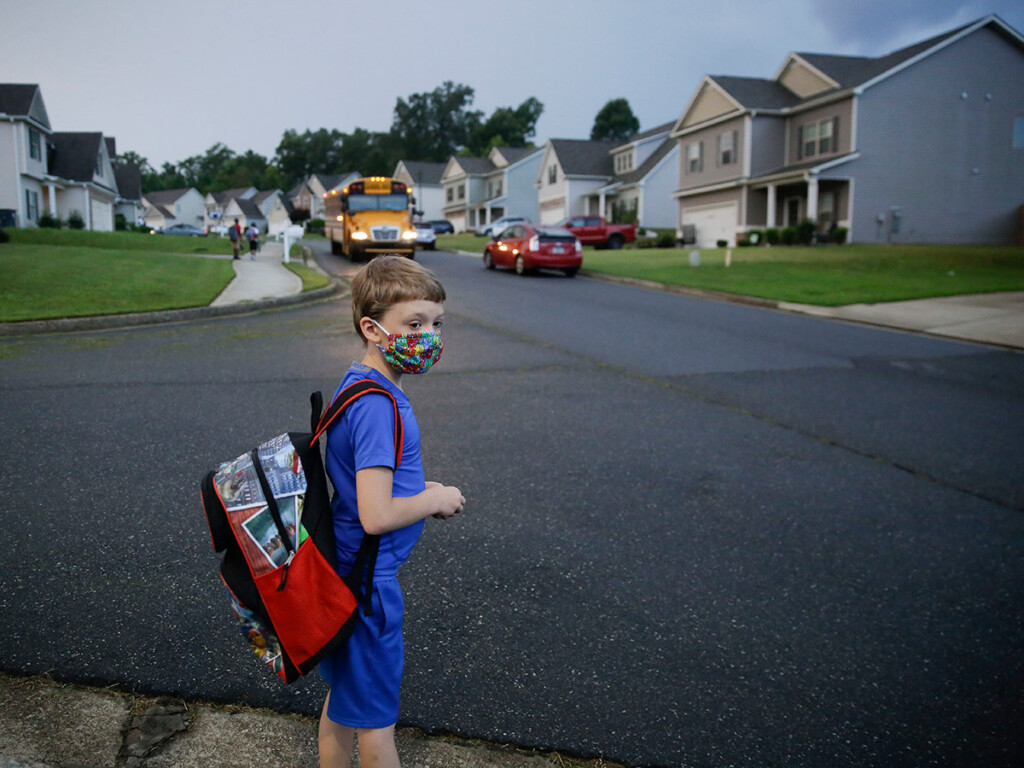 A seven-year-old boy waits at the bus stop in Dallas, Ga., for the first day of school on Aug. 3, 2020.