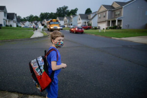 A seven-year-old boy waits at the bus stop in Dallas, Ga., for the first day of school on Aug. 3, 2020.
