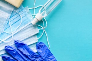 Stock image of medical mask, gloves and sanitizer on a blue background.