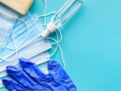 Stock image of medical mask, gloves and sanitizer on a blue background.