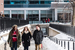 Three students walking together up a ramp during winter
