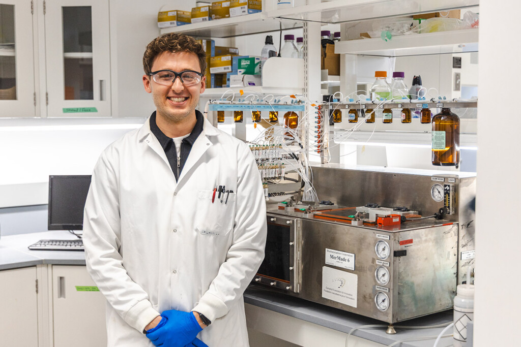 A scientist in a lab, wearing a lab coat and protective goggles.