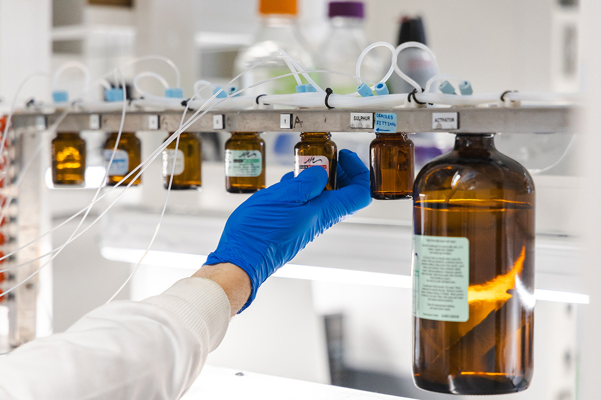A gloved hand reaching for a specimen inside a laboratory.