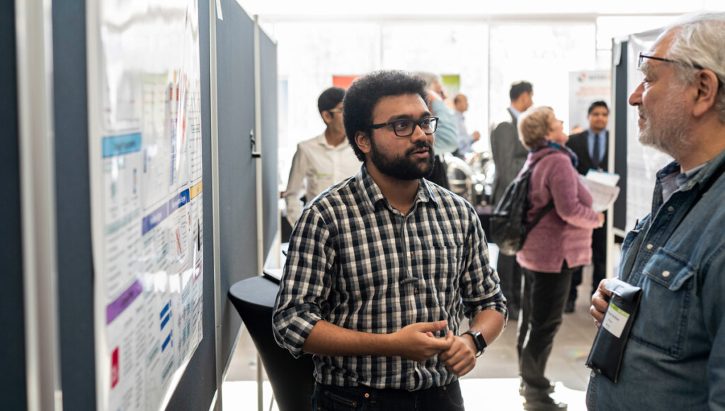 A Data Day 6.0 participant shows his poster competition entry to a judge.