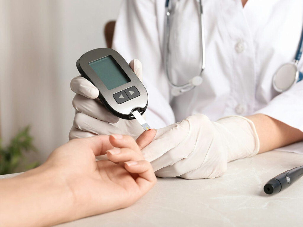 A nurse draws blood from a finger using a small device to test for Type 2 Diabetes.
