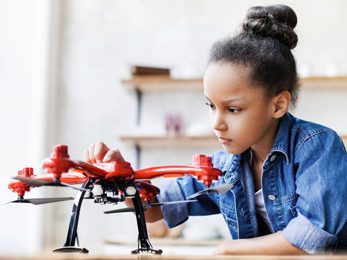 A small chuld plays with a drone.
