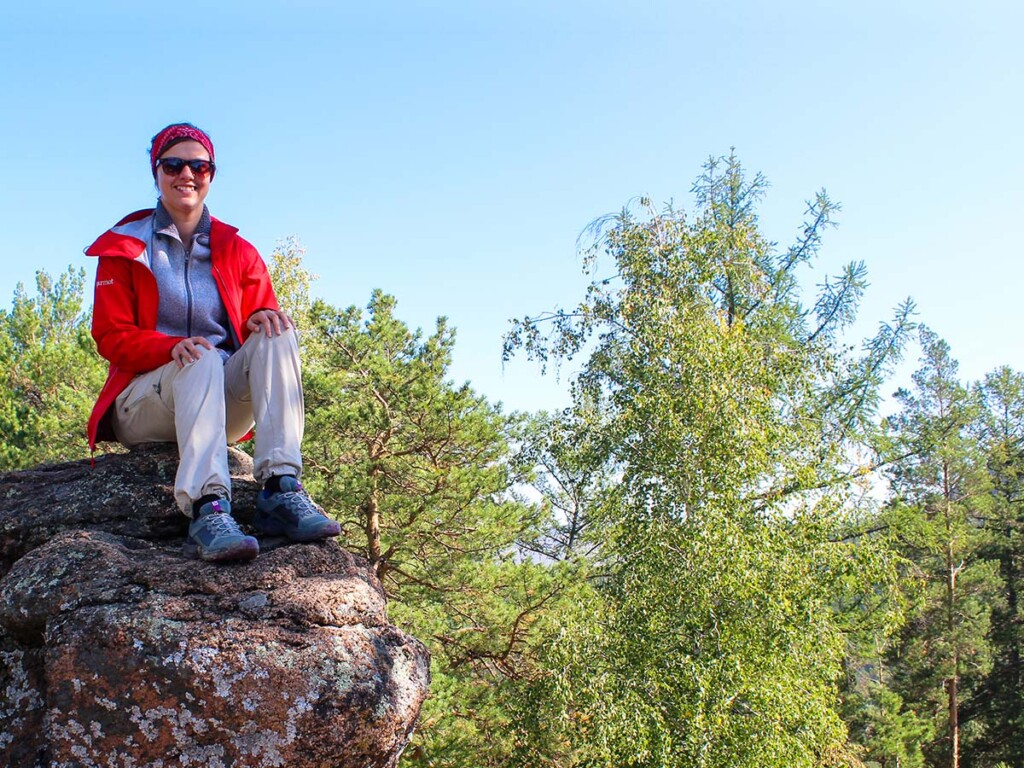 A Carleton University Earth Sciences student sitting on a large boulder.