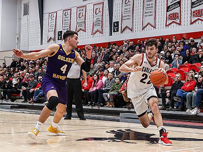 A basketball player drives for the net along the perimeter of the court.