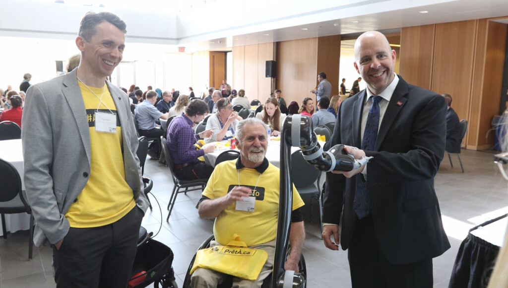 President Benoit-Antoine Bacon shakes a robotic hand during the Enable Ottawa event.