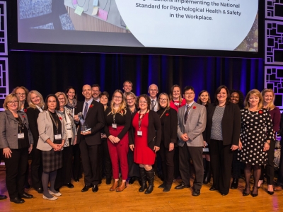 A large group of Carleton faculty and staff members stand together on stage during the Excellence Canada awards ceremony.