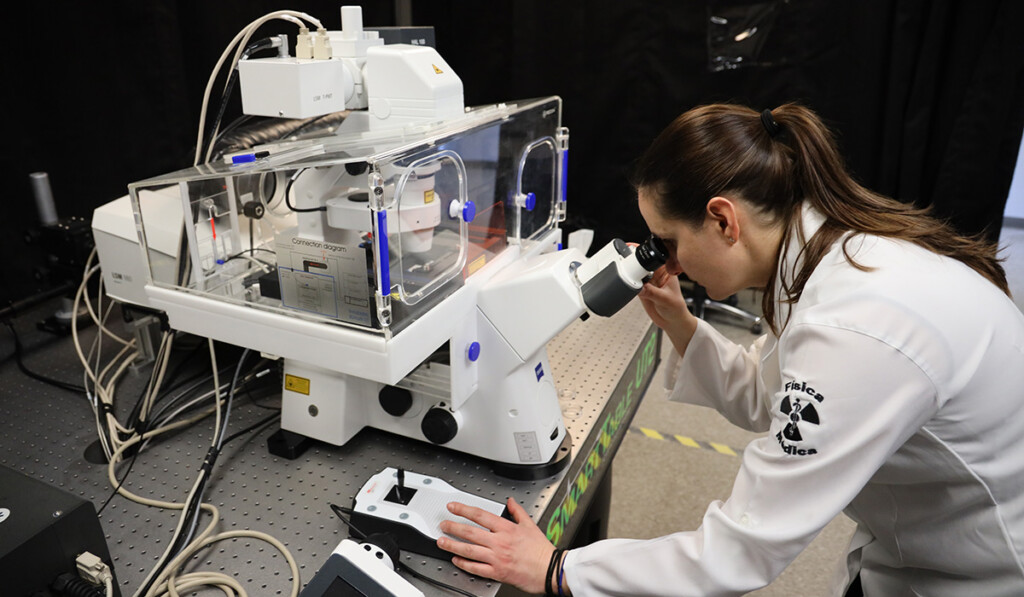 A scientist peers into the lens of a high-powered microscope.