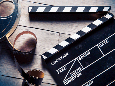 A film reel and wooden clapperboard on a wood floor.