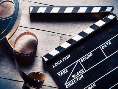 A film reel and clapperboard lie on a wooden floor.