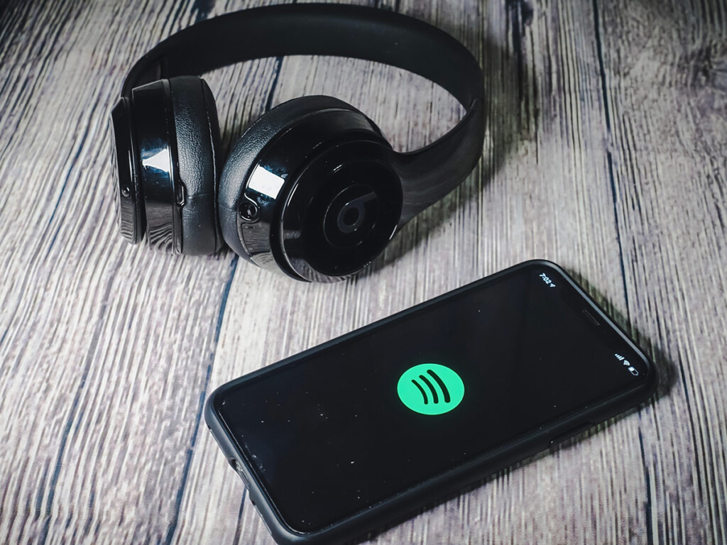 A mobile phone displaying the Spotify logo, next to a pair of Beats headphones.